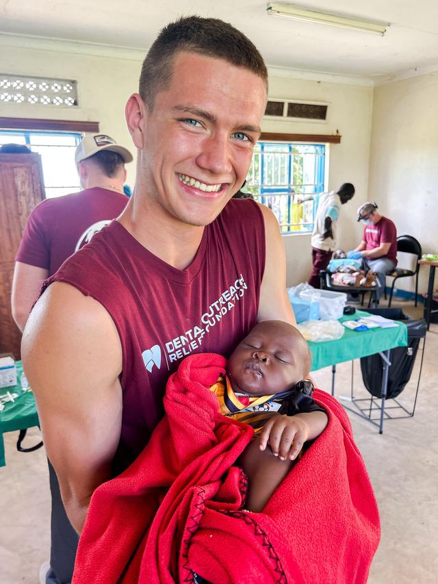A volunteer cradling a baby wrapped in red